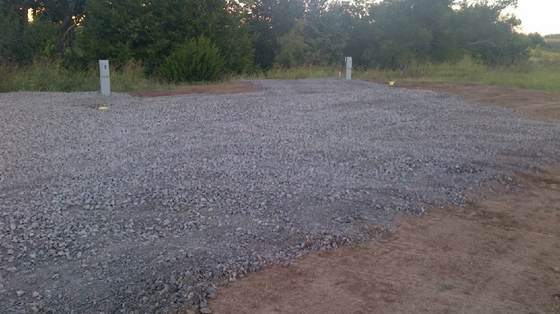 Empty freshly graveled 35-foot-wide RV site with hookup pedestals ready for setup