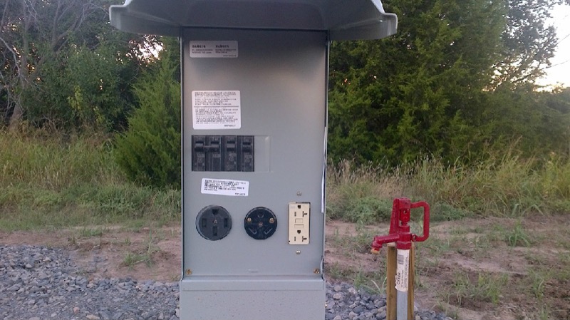 Close-up of a site's 30/50-amp electric hookup pedestal and water spigot